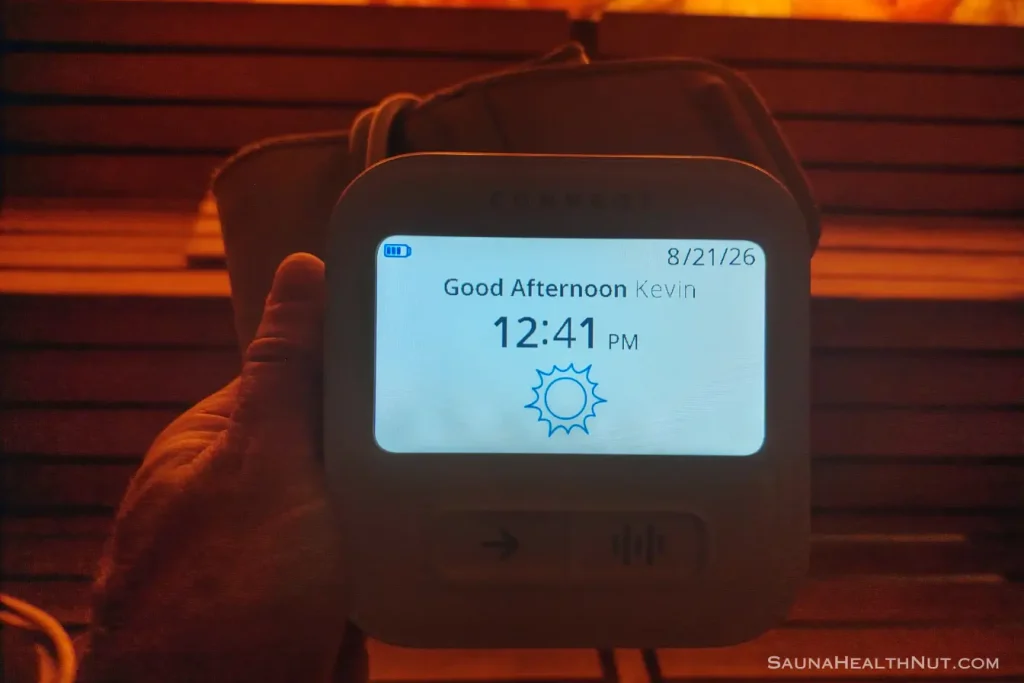 A man holding a CONNEQT Pulse blood pressure device in hand inside a sauna